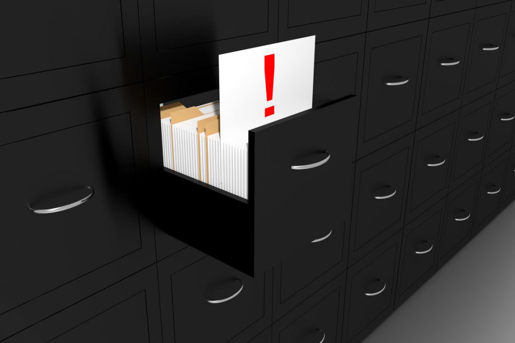 open file cabinet drawer with an open file marked with an exclamation point